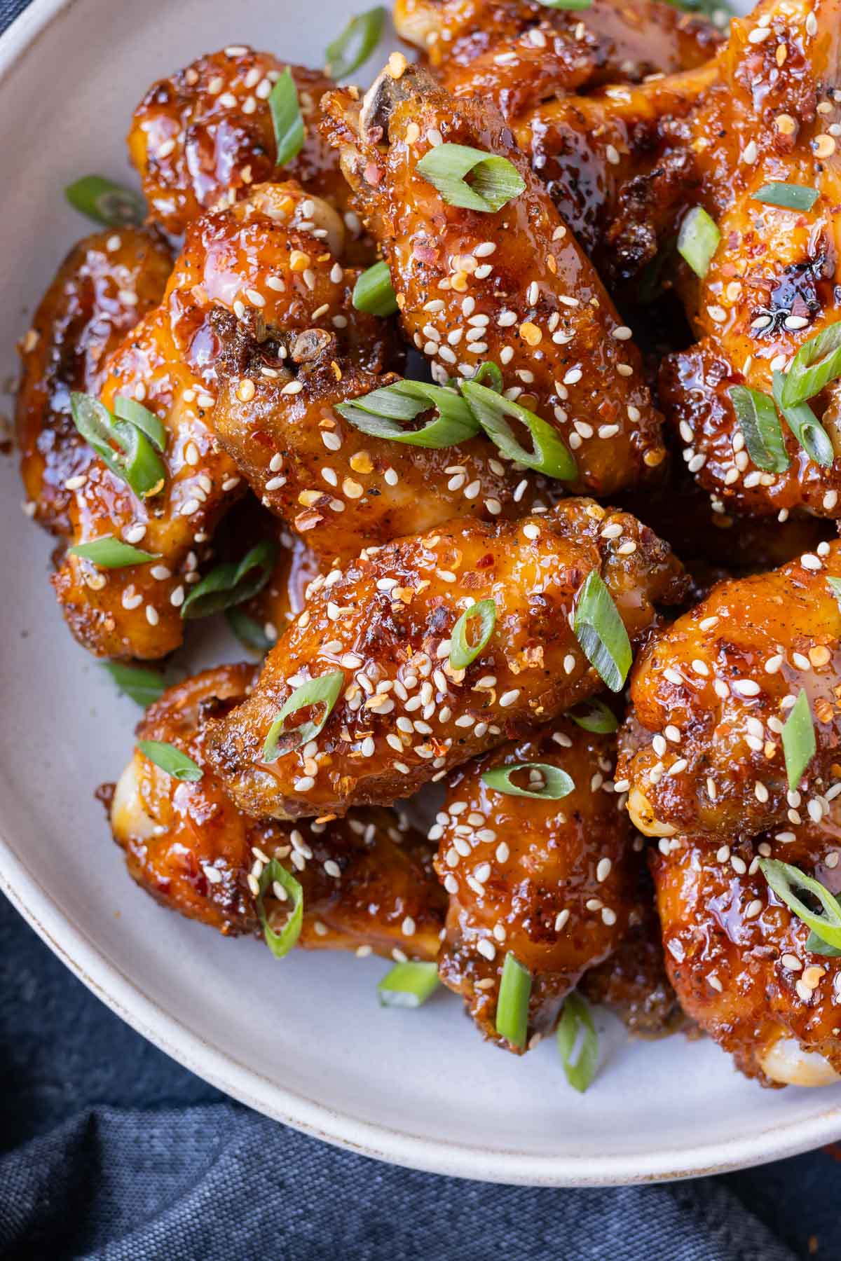 Hot honey chicken wings are stacked in a white bowl for an easy appetizer.