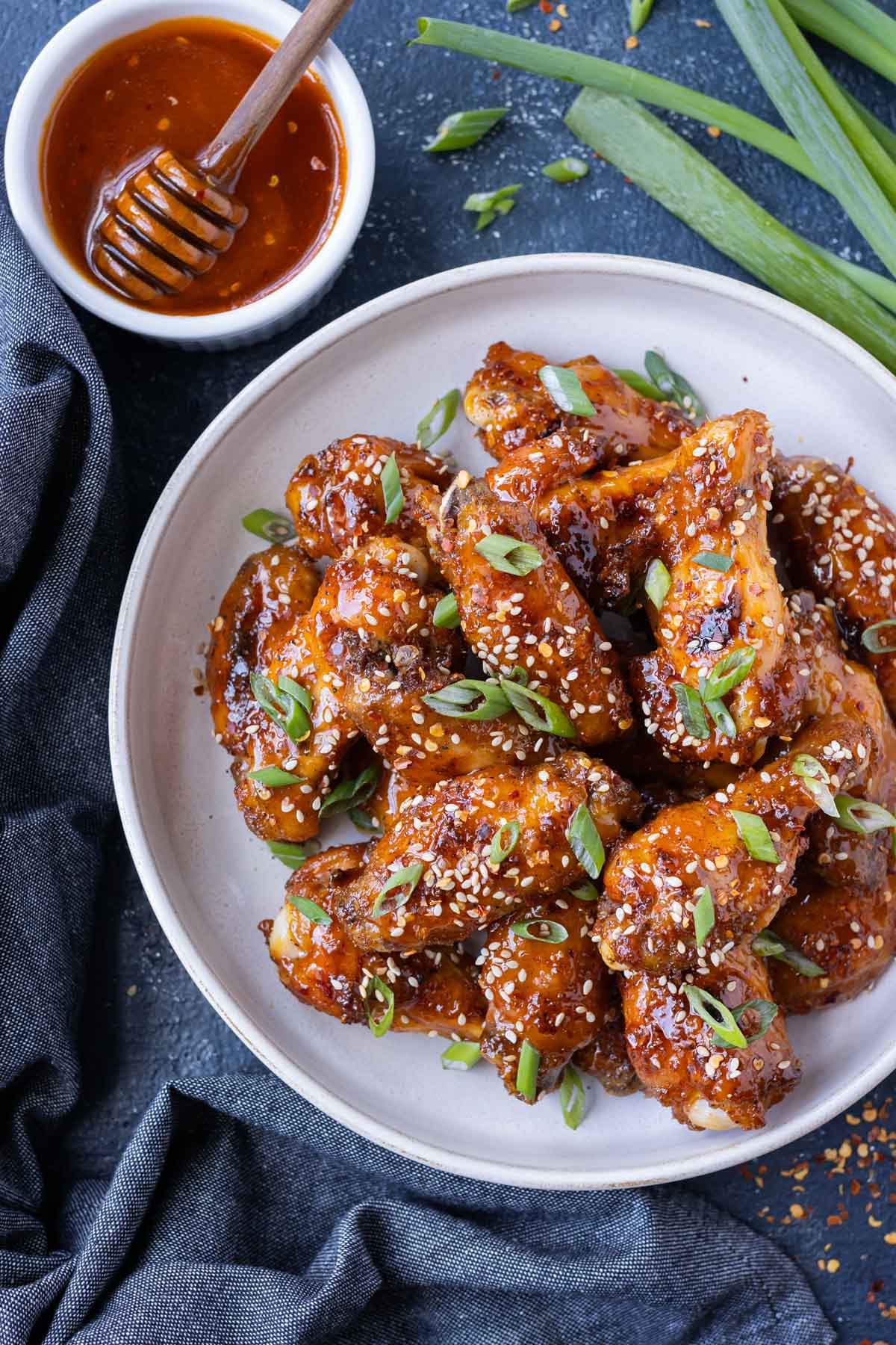 A plate full of hot honey chicken wings are served at an event.