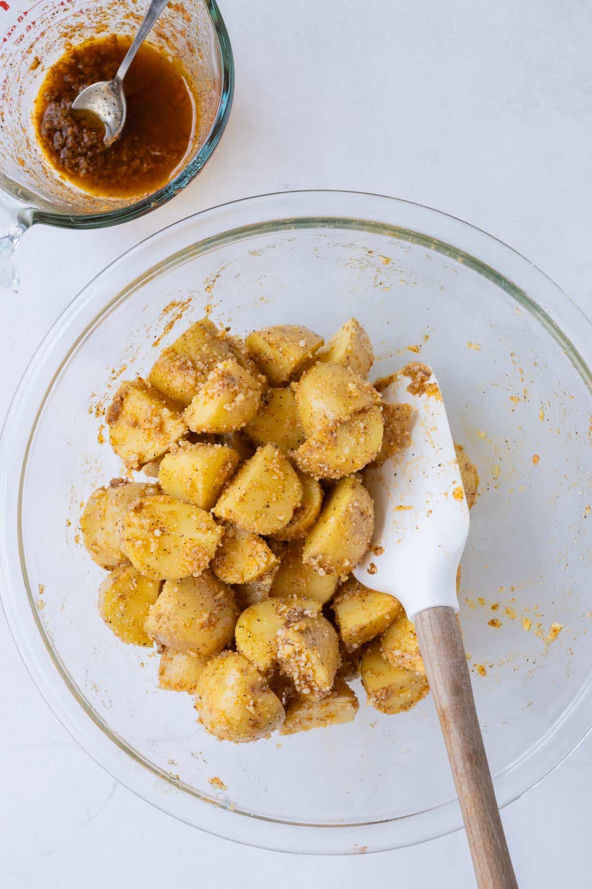 Potatoes are seasoned with a Parmesan mustard sauce in a bowl.