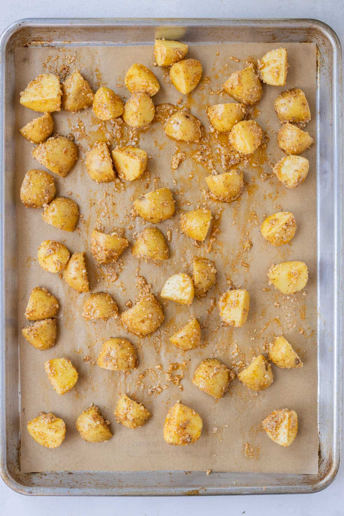 Potatoes are spread across a baking sheet and roasted in the oven.