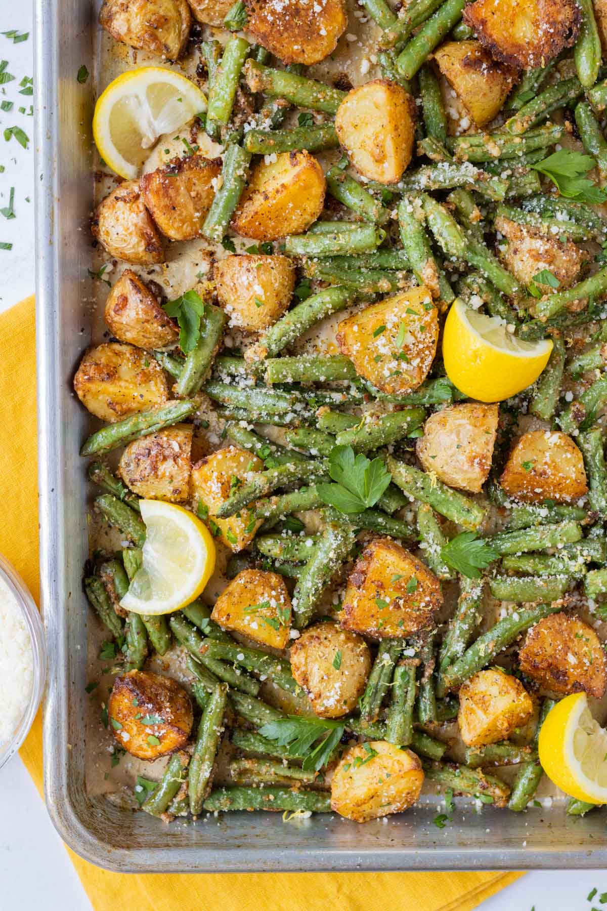 Seasoned potatoes and green beans are spread on a baking sheet to roast for an easy side dish.