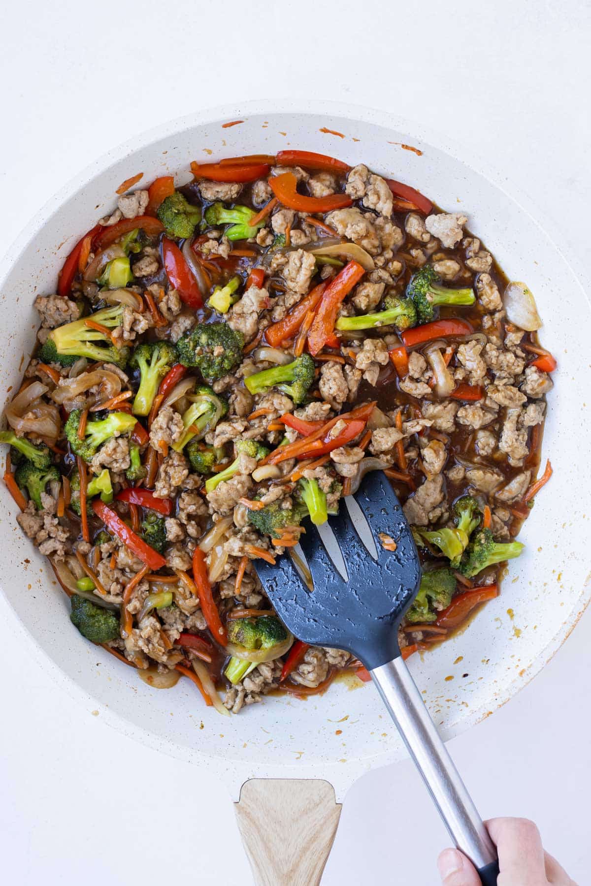 Teriyaki sauce is added to ground turkey and veggies in a skillet for a stir-fry recipe.