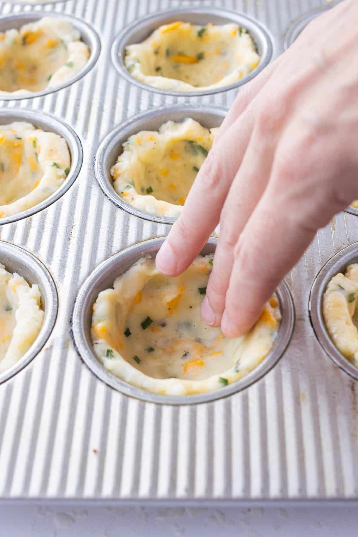 The mashed potato crusts are formed into cups in a muffin tin for a Mini Shepherd's Pie recipe.