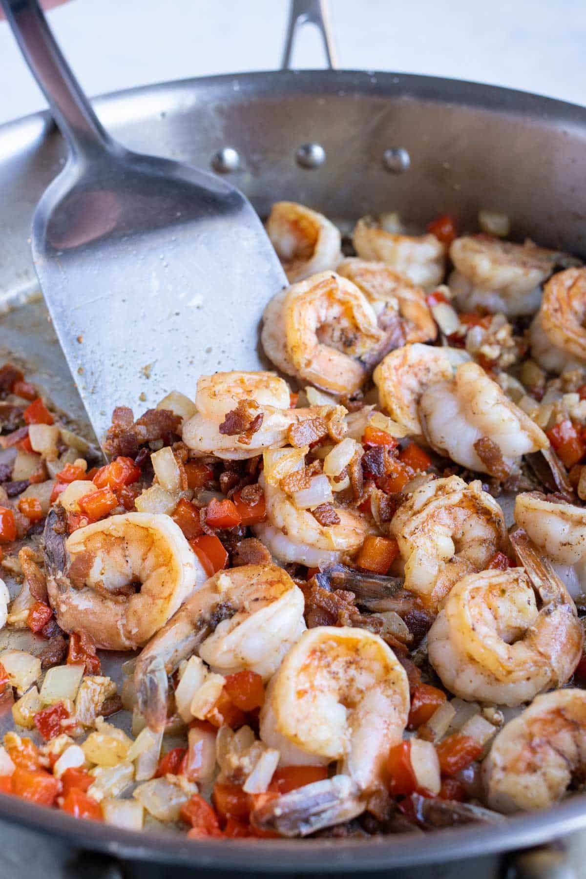 Large gulf shrimp are seared with Cajun blackened seasoning in a skillet.